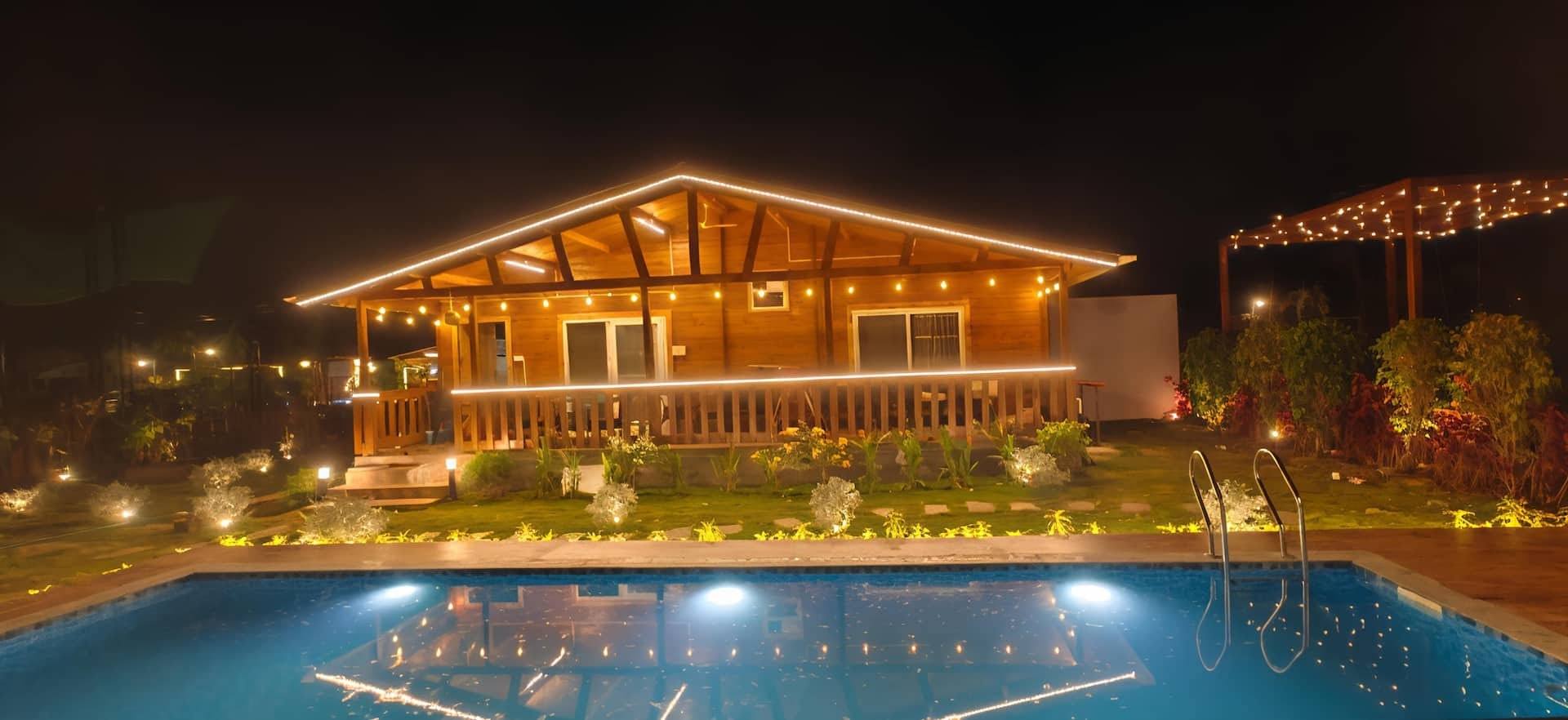 Illuminated cottage and pool at night, wide view